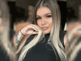 Joven mujer con cabello rubio y maquillaje natural, en un entorno desenfocado.