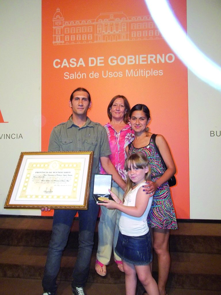 El primer egresado de la UNAJ junto a su familia mostrando el reconocimiento entregado en la Casa de Gobierno (1)