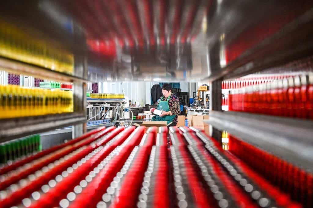 Mujer promociona productos agrícolas y frascos de miel en evento en China, con cajas y paquetes de productos naturales.