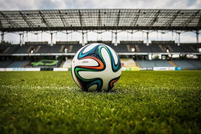 Balón de fútbol en campo de estadio italiano, símbolo del fútbol en Europa.