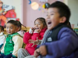 Niños en aula escolar riendo y participando en actividad educativa