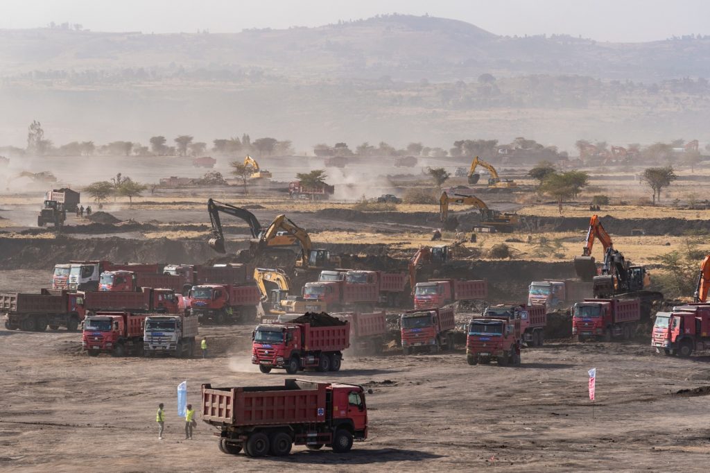 Maquinaria pesada y camiones trabajan en una obra de infraestructura financiada por empresas chinas en África.