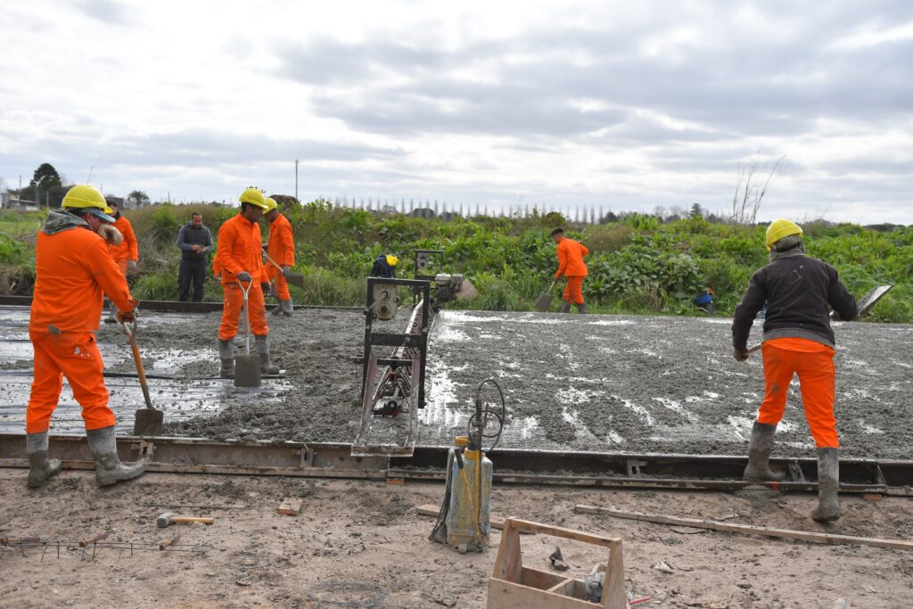 Obreros realizando tareas de hormigonado en la obra de pavimentación de la calle Cariboni, en Florencio Varela.