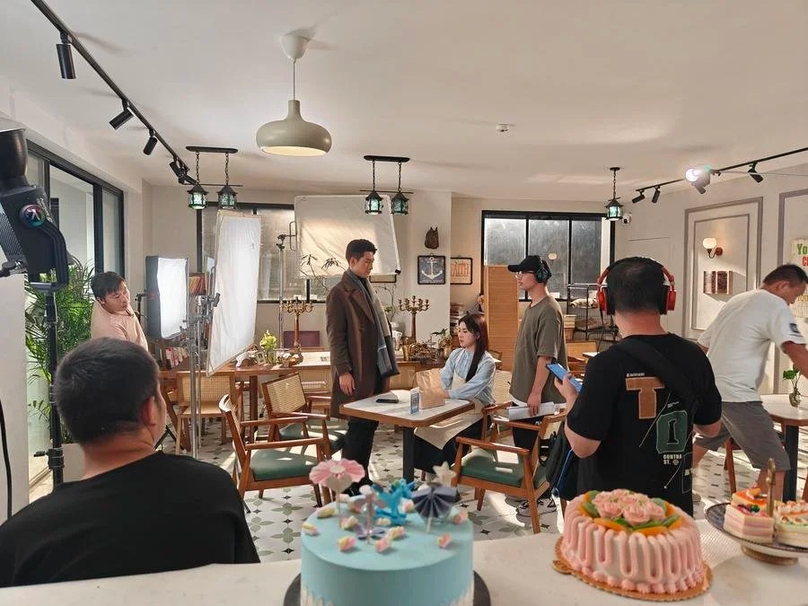 Equipo de filmación chino rodando una escena de microdrama con pantalla vertical en un set que simula una cafetería.